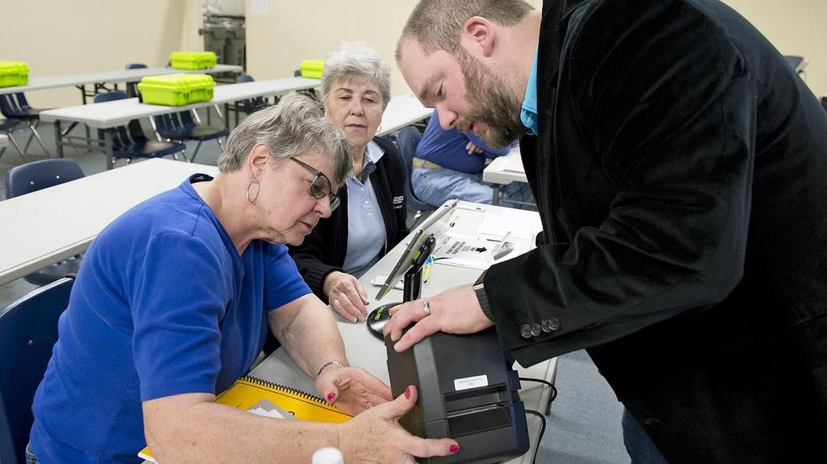 Kay Williams of Overland Park (left) and Jean Branson of Gardner looked on as election manager Matt Woehrle (right) connected a printer as part of a training session on the new Poll Pad, a device that election workers will use to check in voters for the April election.