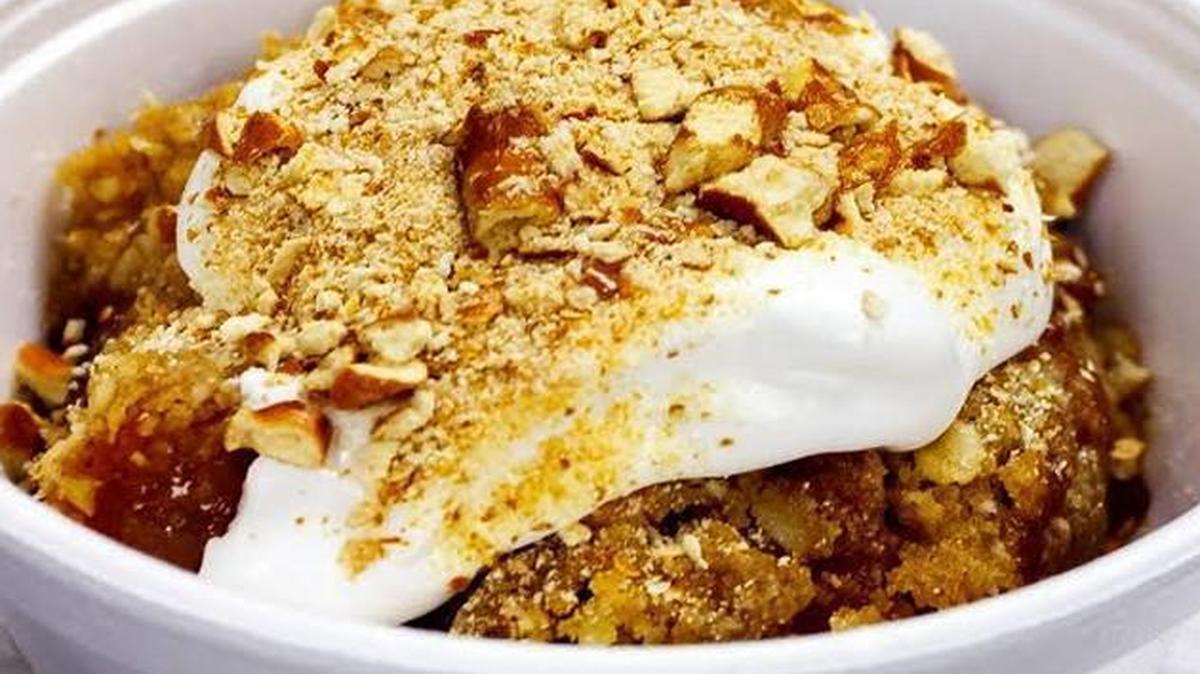 Apple Crisp with warm Granny Smith apple and raisin filling, a baked oatmeal streusel, whipped cream topping, and chopped salted pretzels.