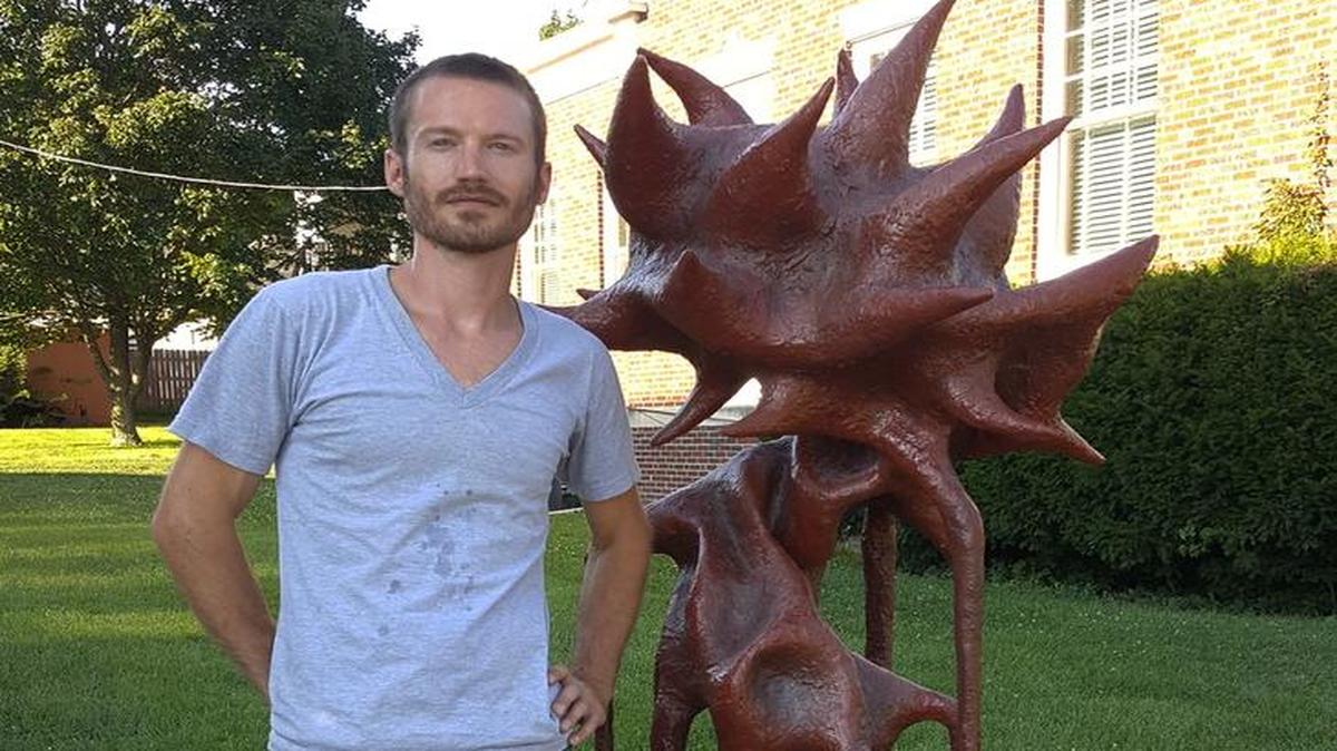 Sculptor Jacob Burmood with Plumb Twisted, a sculpture made of steel, fiberglass, resin, red iron oxide and graphite. The work is the first of three sculptures to be chosen for the Public Arts Sculpture Program. It will be on display at a park near the Clay County Archives in Liberty for one year.