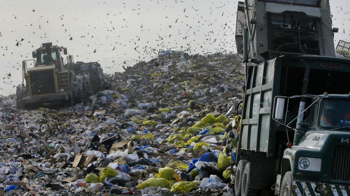 From several years ago, a bulldozer worked on flattening a mound of trash dumped at the Johnson County Landfill while a trash truck, right, dumped off more trash at I-435 and Holliday Drive in Shawnee.
