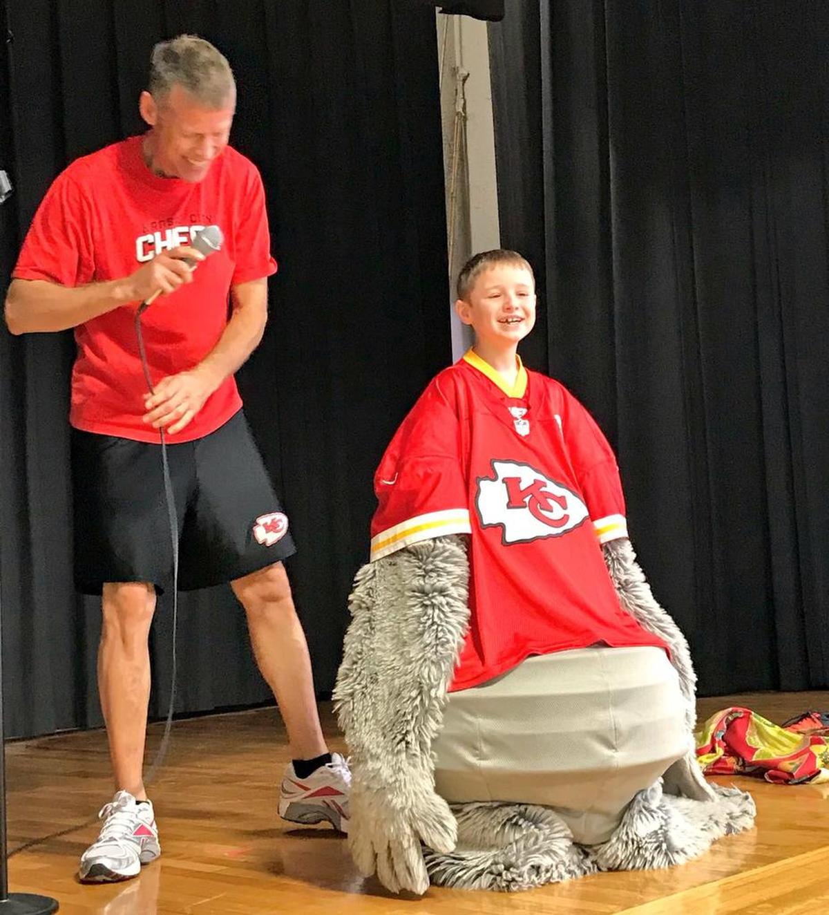 KC Wolf Dan Meers (left) lets Greenwood Elementary School third-grader William Hunter try on his Chiefs mascot gear during the school’s Red Ribbon Week assembly.