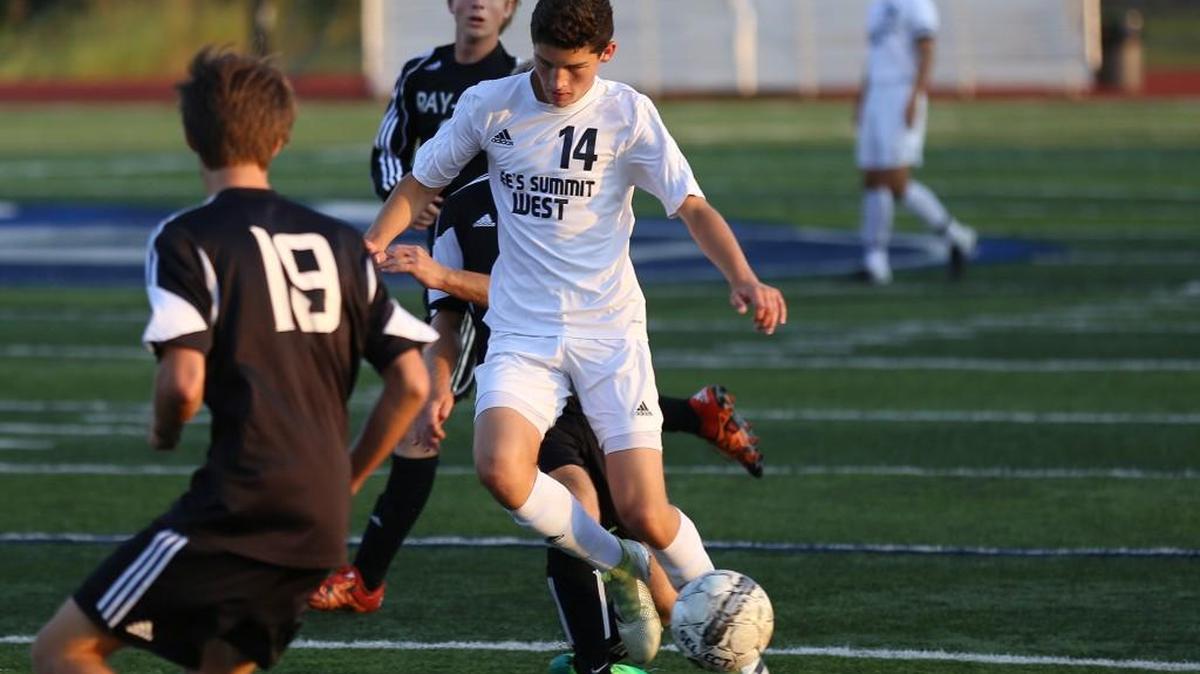 Drew Meara of Lee’s Summit West tries to get around Josh Thomas (left) and another Raymore-Peculiar defender. Meara scored the first of two penalty kicks for the Titans in their 3-0 victory Monday at West.