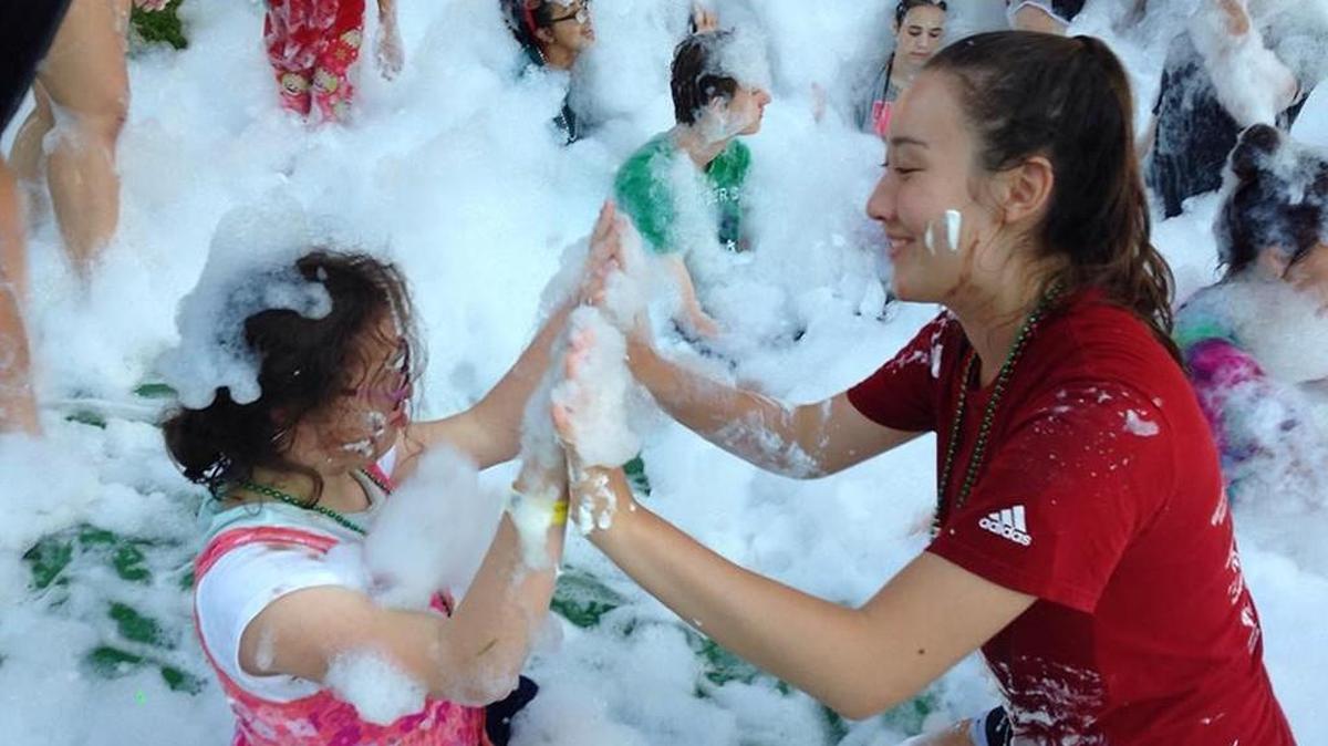 Summit Christian Academy senior Rayna Cross enjoys bubbles during the “Messy War” with her young buddy at Camp Blessing in Brenham, Texas.