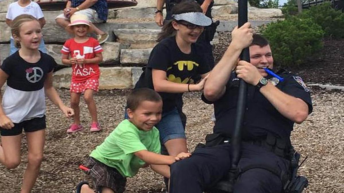 Officer Jordan Clapp playing with children at Lea McKeighan Park, part of the Cops in the Community program of Lee's Summit Police Department, which recently received its fourth accreditation by the Commission on Accreditation for Law Enforcement Agencies.