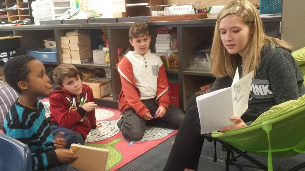 Eighth-grader Jadyn Hanners shares her book with students from Pleasant Lea Elementary School.