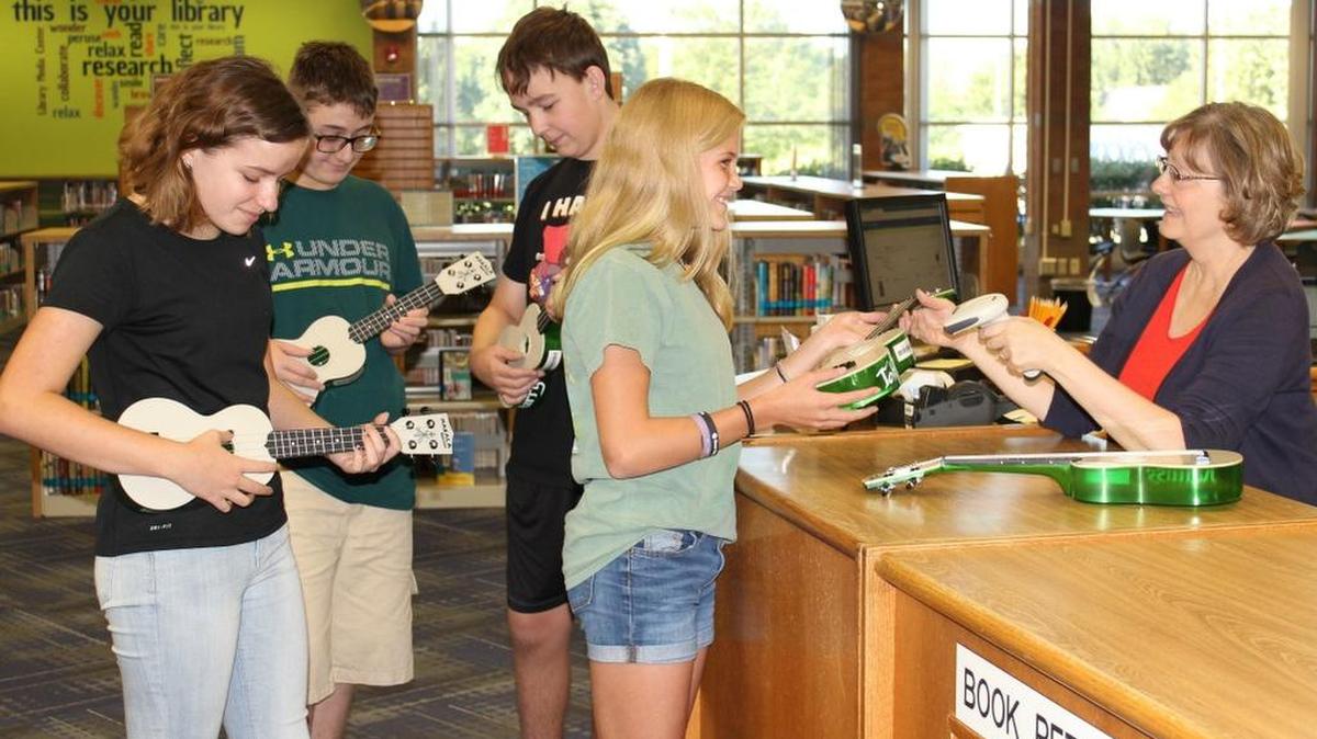 Summit Lakes Middle School students (from left) Morgan Bicknell, Thomas Andrews, Andrew Zoellner and Katie Carroll check out ukuleles from the school’s library in Lee’s Summit. The library started checking out the stringed instruments earlier this month in an effort to offer something more non-traditional for students and staff members.