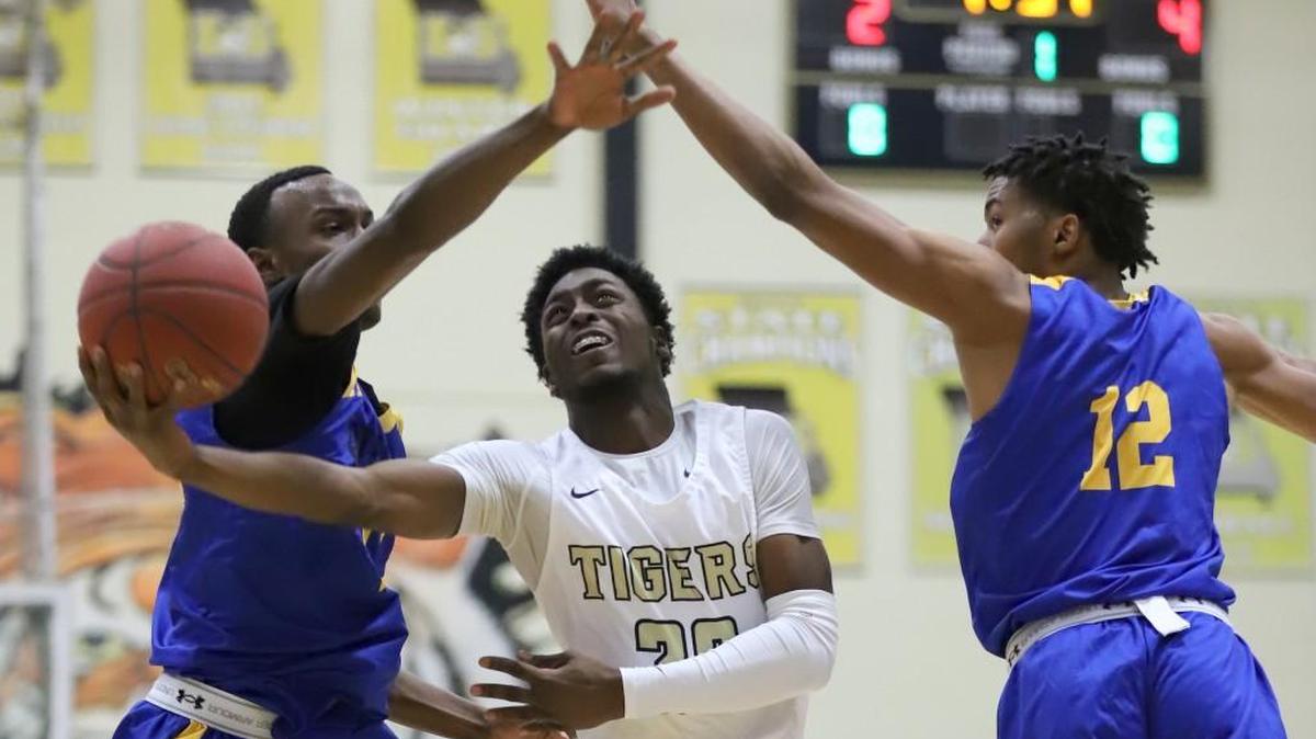 Lee’s Summit’s Landen Willis (center) slipped between two Ruskin defenders for a shot Monday during a first-round game in the 43rd Culver’s Classic Monday at Lee’s Summit. The Tigers fell behind early and lost 62-45.