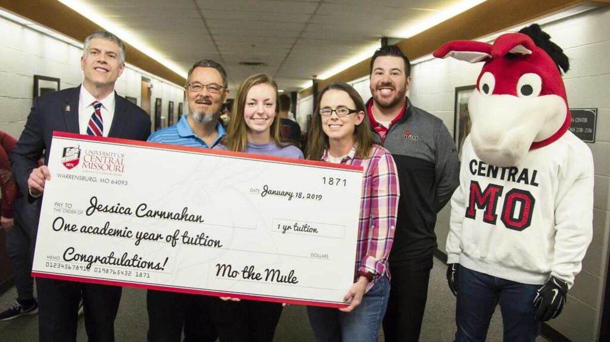 UCM Interim Provost Mike Godard and Assistant Vice Provost Drew Griffin joined the UMC Mascot, Mo the Mule, in presenting a check to Jessica Carnnahan and her parents Lester and Becky Carnnahan to represent the one year of free tuition Carnnahan won as a giveaway sponsored by the school.