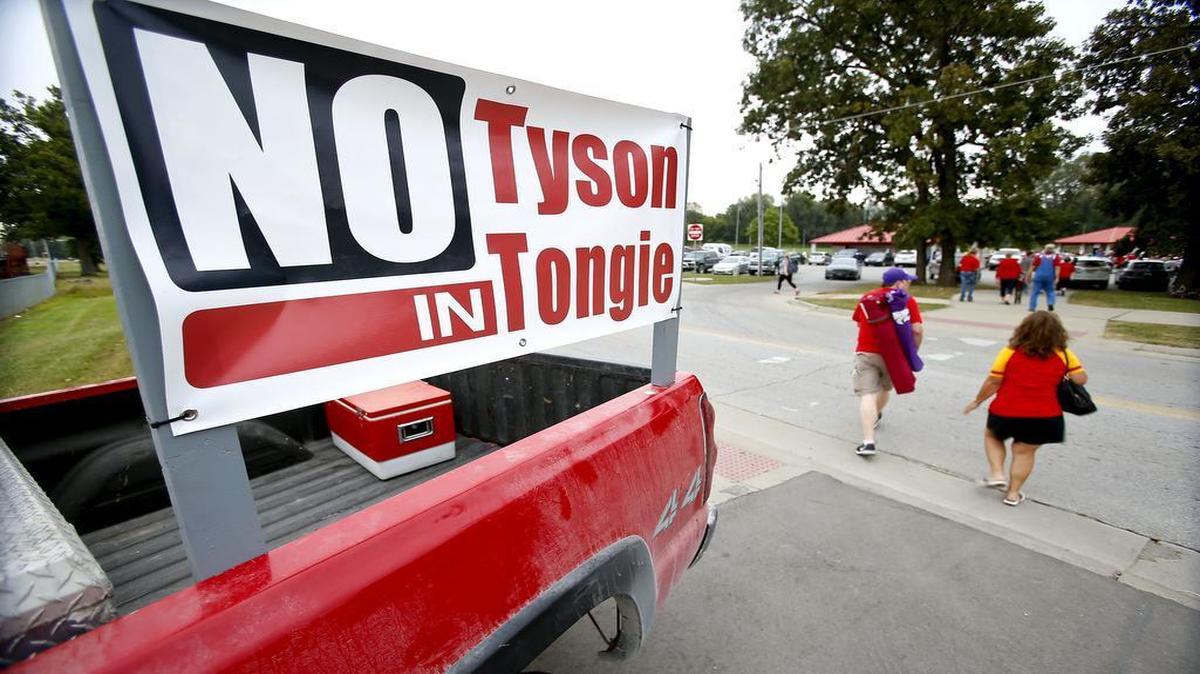 A couple walk across the street to Chieftain Park, where a rally in opposition of a Tyson Foods plant being built near the town was held, Friday, Sept. 15, 2017 in Tonganoxie, Kan.