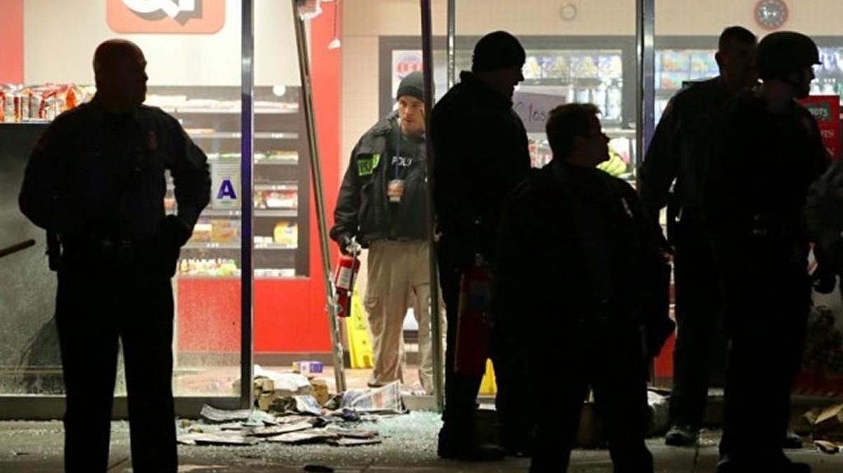 A police officer with a fire extinguisher stands in the broken out entry to a QuikTrip on Dec. 24, 2014, after a shooting nearby in Berkeley, Mo.