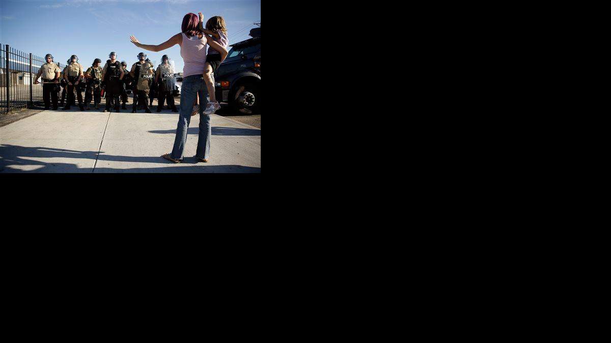 
Like protester Janelle Pittman, some parents let their kids witness the events in Ferguson, Mo. Pittman on Wednesday held her daughter as police stood guard.
