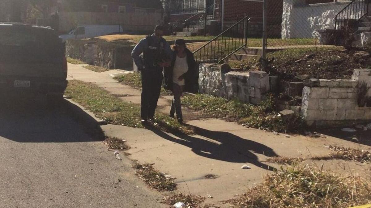 A Kansas City police officer walks with a woman who arrived at a homicide scene Monday morning in the 4300 block of East 25th Street.