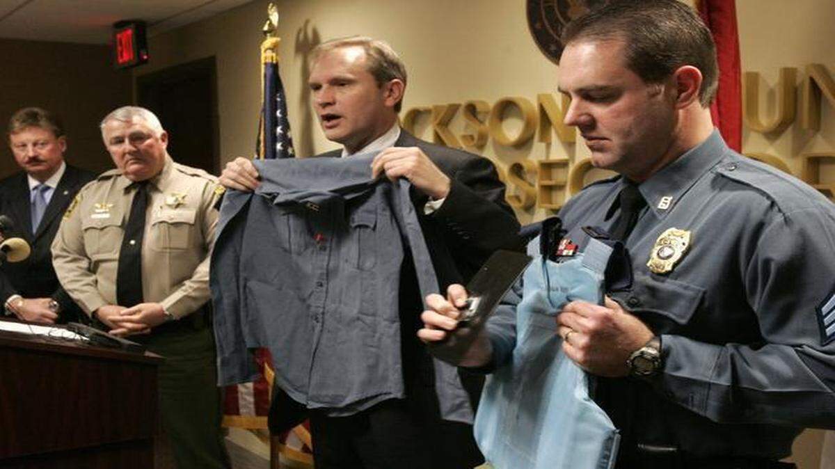 
As the Jackson County Sheriff’s Department’s Ben Kenney (from left) and Hugh Mills looked on in 2009, former Kansas City police officer Patrick Brown showed the shirt he was wearing when he was shot in the chest by Saeed Aquil on Dec. 31, 1994. Sgt. Larry Schoen, who was a police officer and Brown’s partner at that time, showed Brown’s bullet-resistant vest, which saved his life. 
