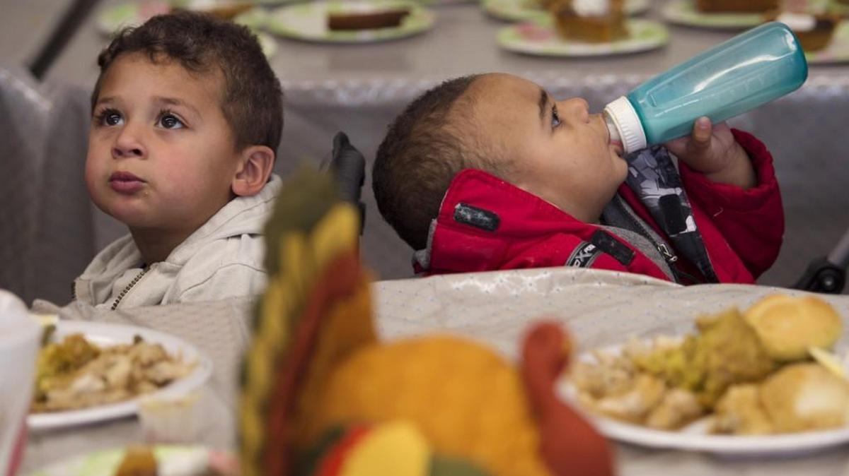Two-year-old Joshua Lane (left) asked his father, Adam Crowder of Grandview, for more food as his brother, 1-year-old Joseph Lane, continued to work on his bottle during a past Salvation Army Thanksgiving meal.
