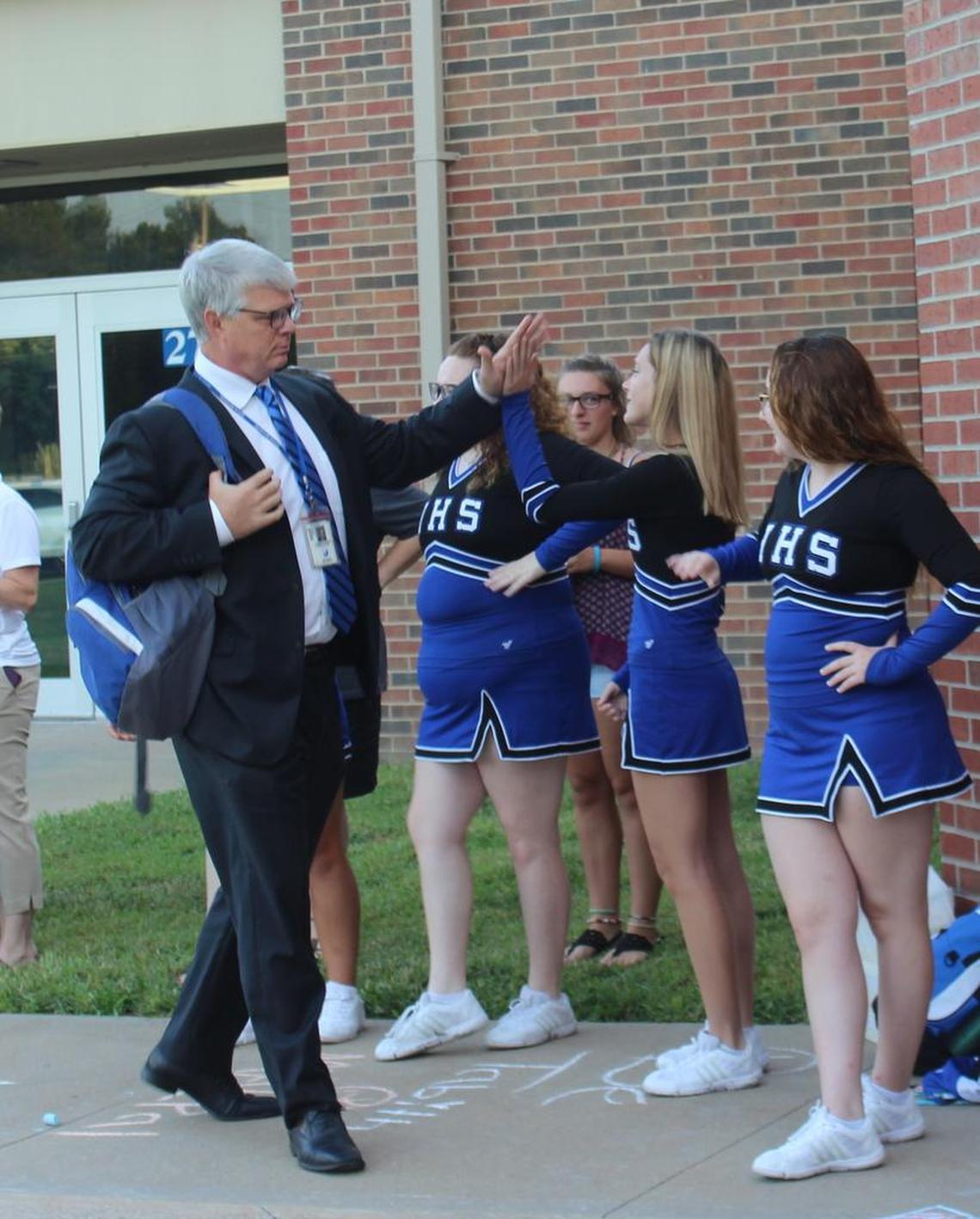 Harrisonville High School cheerleader Emily Sullivan gives a high-five to middle school principal Chris Grantham.
