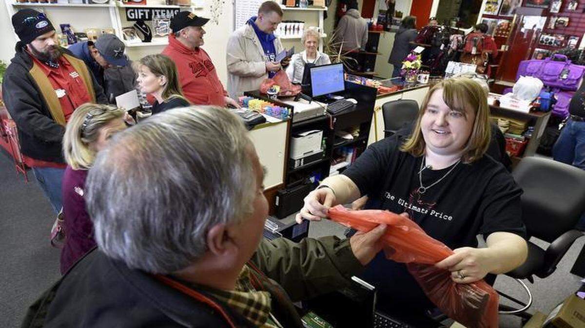 
Becky Bieker, owner of She’s A Pistol gun shop in Shawnee, was back behind the register Friday after the store reopened for business. Business was brisk as many loyal customers, including Ray Erlichman (front) of Shawnee, came in a show of support for the Bieker family.
