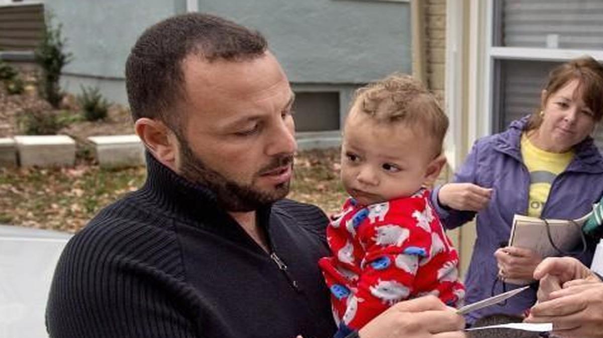 A Syrian refugee family that recently arrived in Independence includes the father, Ibraheem Alkhwaja (left), shown holding his 1-year-old son Mohamad. Alkhwaja’s wife is Enas Hajah (second from right); the family is being helped by neighbors Jeff Rogers (right) and Cindi Rogers (third from left). The family’s saga began when they fled violence in Syria four years ago. Here the neighbors help the refugees understand their mail.
