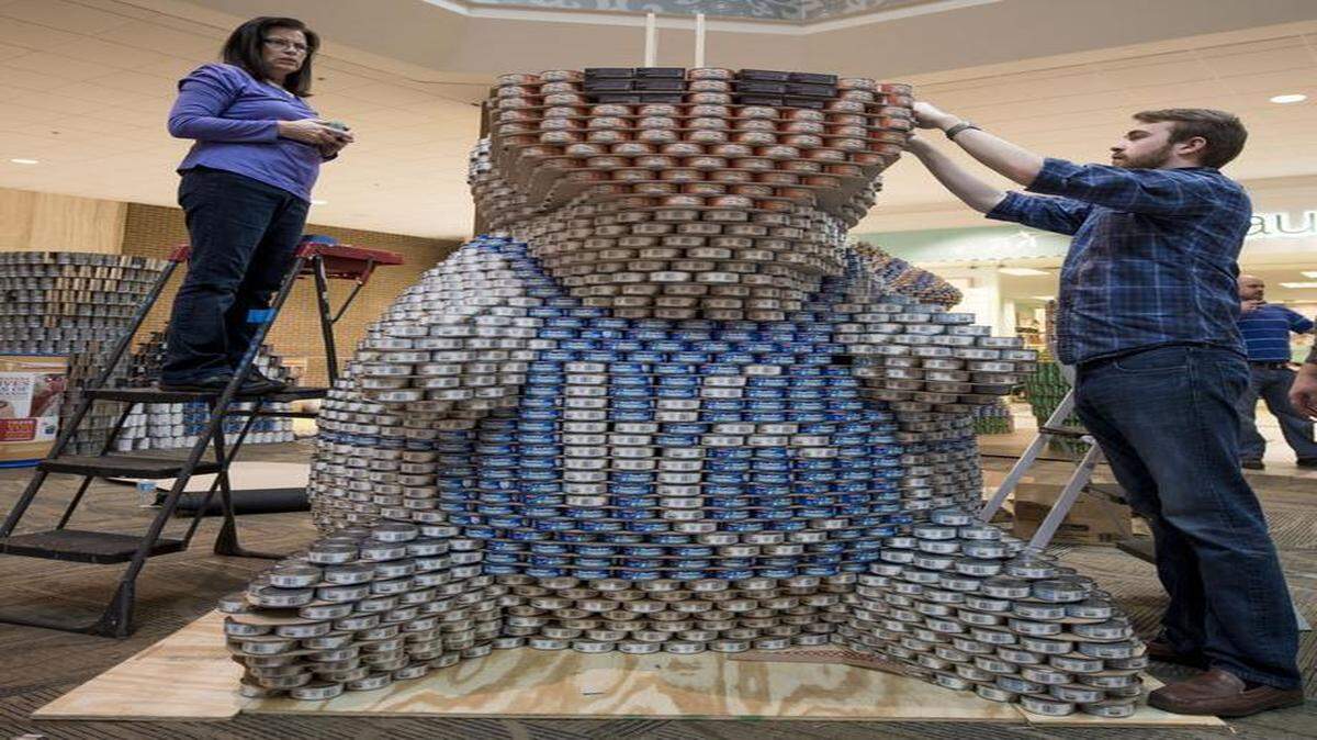 
Connie Lauer (left) and Mike Fahey of ACI Boland Architects helped create a can sculpture called “We Can Tailgate to Stop Hunger” on Wednesday at Oak Park Mall. Entries in the Canstruction benefit for Harvesters will be on display through March 5.

