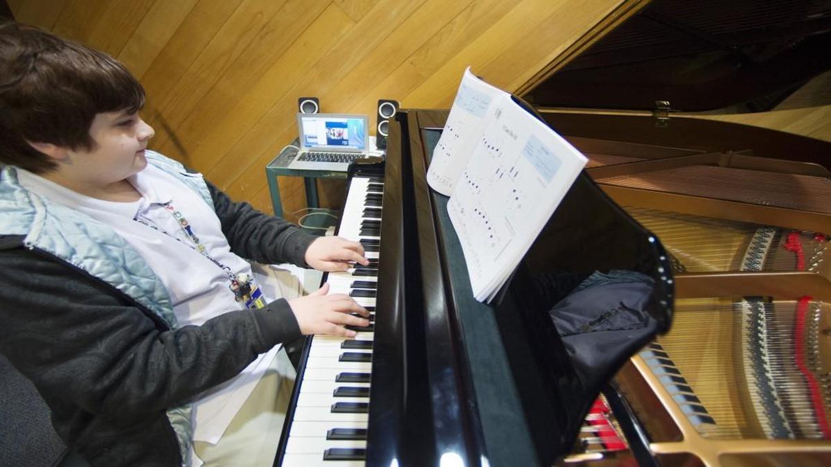 Miguel Gonzales, 12, a sixth-grader at Eisenhower Middle School, played the piano while receiving lessons from Paul Adams, who was on the University of Kansas campus. The pianos were linked, allowing Miguel and Adams to perform on the keys at the same time without having to be in the same place.