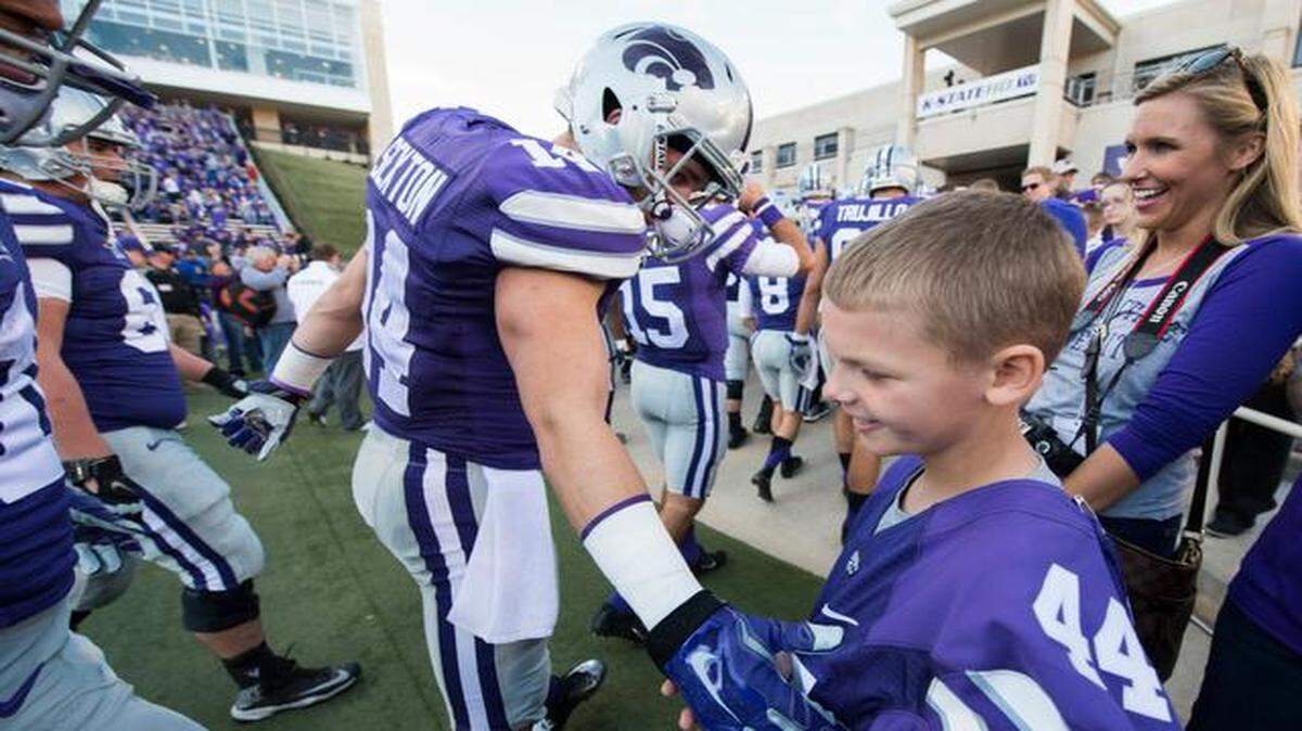 
Kaiden Schroeder, 9, was all grins Saturday as he slapped hands with K-State players, including wide receiver Curry Sexton, as the team warmed up in Manhattan before K-State defeated Kansas 51-13. Kaiden’s journey with the team will take him to a bowl game with his family thanks to generous donations by the “K-State family.” 
