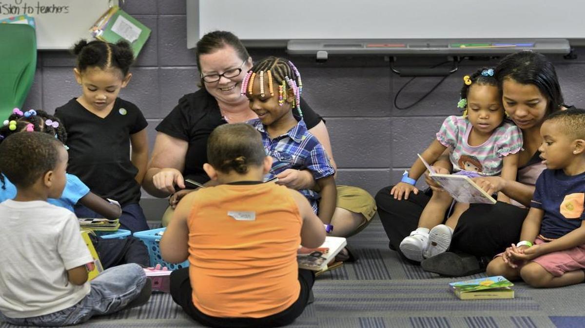 Teacher Jennifer Maddux (left) and paraprofessional Shakyra Washington read books to their prekindergarten class at an early learning center operated at Ervin Junior High School in Kansas City by the Hickman Mills School District. The learning center is one of several local attempts to boost early childhood education.