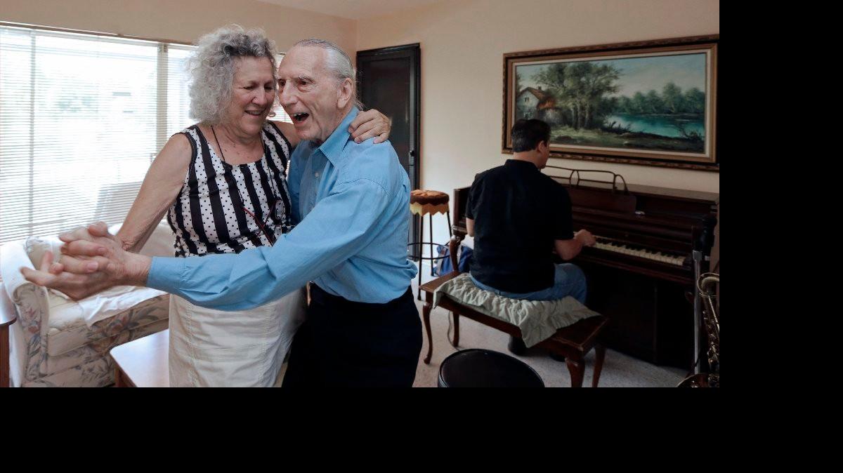 
In this May 11, 2015 photo, Al Karp, right foreground, and his wife Saundra, left, dance to the music their son Larry, background, plays on the piano at their home in North Miami Beach, Fla. The trio performs old standards locally as the Karp Family to ease stress and help raise money to save their home from foreclosure.
