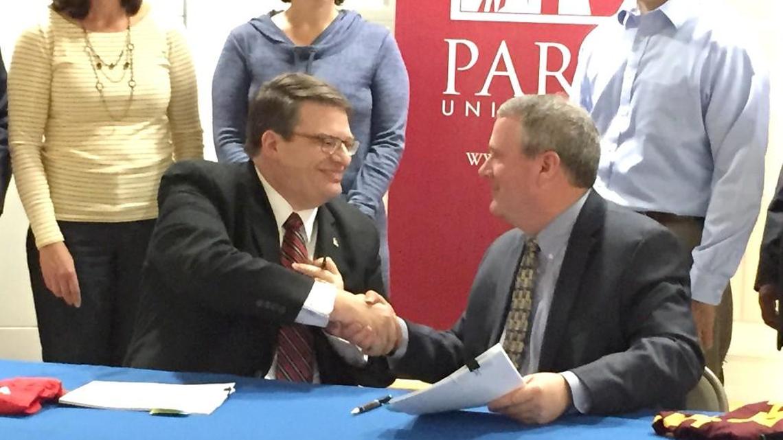 Park University President Greg Gunderson (left) and Lenexa Mayor Michael Boehm sign a deal to bring a Park University campus to Lenexa’s new City Hall.