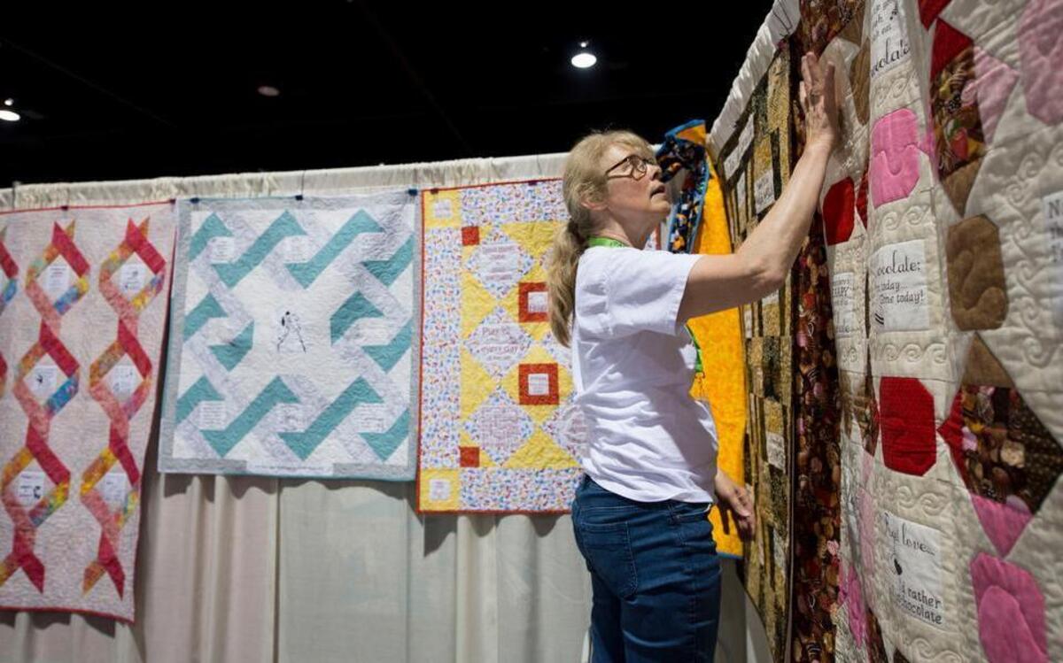 
Joan Linahon of Nevada, Iowa, smoothed out a quilt while helping set up the Block Party Studios booth for the Kansas City Regional Quilt Festival at the Overland Park Convention Center.
