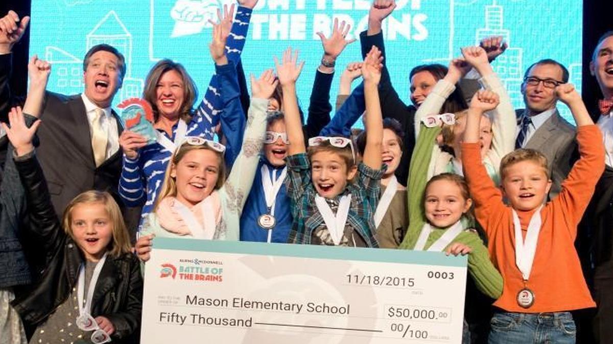 Students from Mason Elementary School in Lee’s Summit were announced Wednesday as winners of the grand prize of the Battle of the Brains competition during an awards ceremony at Union Station. The competition is sponsored by Burns & McDonnell. The students, winners of $50,000 for their school, celebrated on stage with their gifted education teacher Jenny Reidlinger (back row in blue); Greg Graves (far left) of Burns & McDonnell; and George Guastello (far right) of Union Station. The students designed a “Not So Simple” playground that will be built outside at Union Station.
