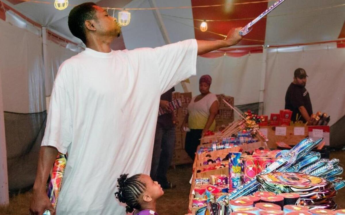 T.J. Slaughter held up a sword-shaped firework as his daughter, 3-year-old Xiolee Slaughter, both of Kansas City, watched on Saturday at a fireworks stand on Holmes Road.