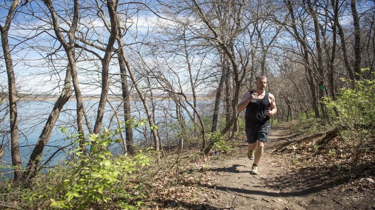 A trail runner jogs along a trail at Wyandotte County Lake Park in Kansas City, Kan.