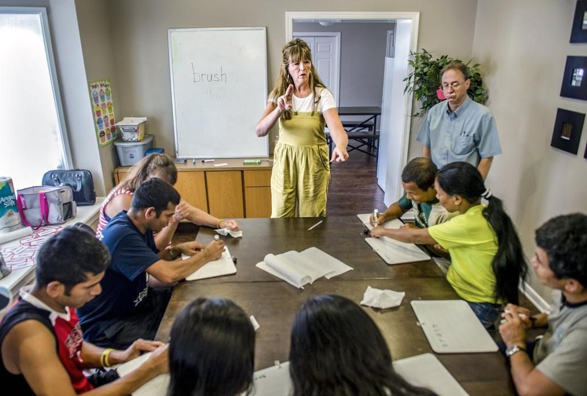The Rev. Debbie Buchholz (center) leads an American Sign Language class for deaf refugees in Kansas City, Kan. Near Buchholz is volunteer tutor John Kingsley (right). Buchholz, who is hard of hearing herself, runs a program for deaf refugees through her Olathe church.
