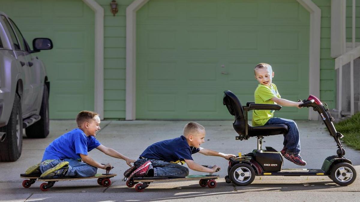 
Zane Jacobs is part of a double-blind University of Kansas trial to find a treatment for Duchenne muscular dystrophy. Zane sometimes uses his power scooter to pull brothers Taegan (center) and Aidan at their home in Eudora, Kan.
