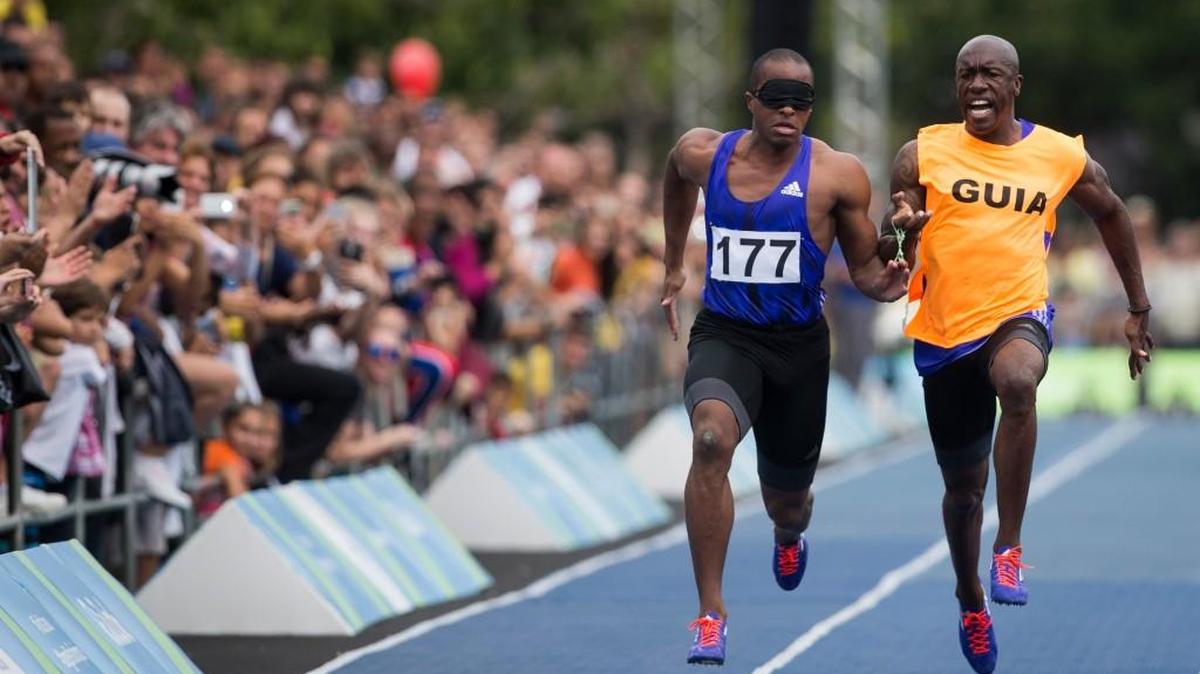 David Brown (left), the fastest blind sprinter in the world, runs with his hand tethered by elastic to a guide, as seen in this photo from Brazil last September. The Kansas City native will be running Sunday in the 4-mile Trolley Run, a race benefiting the Children’s Center for the Visually Impaired, which he attended as a child.