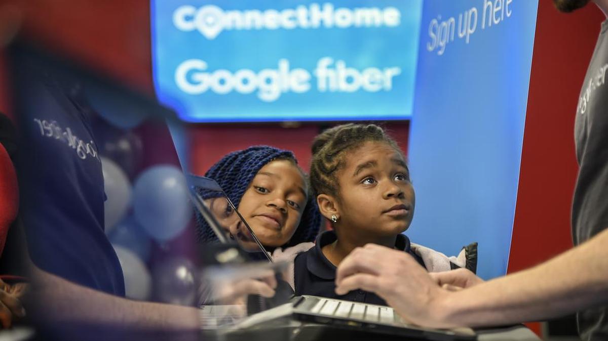 Jazmine Davis, 10, left, and her sister, Terrianna Boone, 8, right, looked on with curiosity as their mother signed up Google Fiber service at the West Bluff housing complex on Wednesday afternoon. West Bluff became the first 100 apartments to receive the super fast Internet connection at no charge to residents under the ConnectHome federal program. The sisters were looking forward to "playing games and watching YouTube videos."