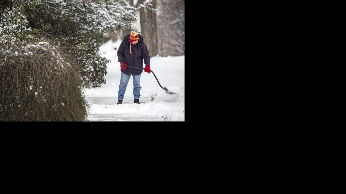 
Karen Regan of Roanoke cleared her sidewalks of snow early on Monday morning after a Sunday night snowfall covered the metro area.
