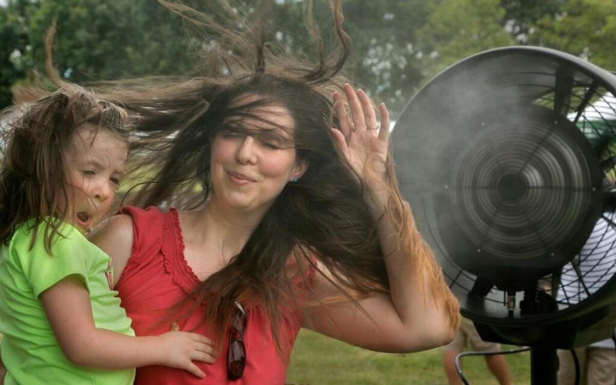 As heat indexes rose into the triple digits, Roma Valentine and her 4-year-old daughter, Payton, of Kansas City, cooled off at a misting fan during the Cultivate Festival in Penn Valley Park. The festival featured chef demonstrations, music and plenty of food and drink.