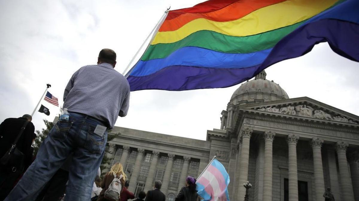 In this March 21, 2016 file photo, gay-rights supporter Mathew Mauldin holds a flag during rally outside the Capitol in Jefferson City.