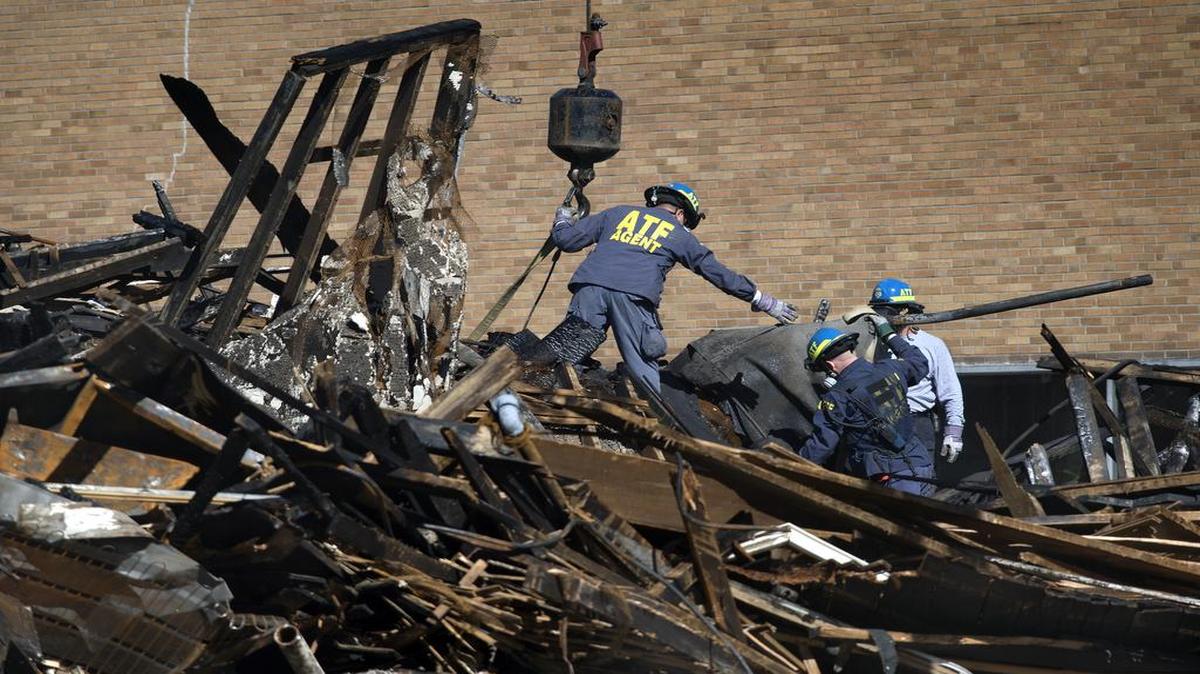 
ATF agents connected straps to a crane Friday as debris was lifted away from the burned-out remains of the building at Independence and Prospect avenues where two firefighters died.
