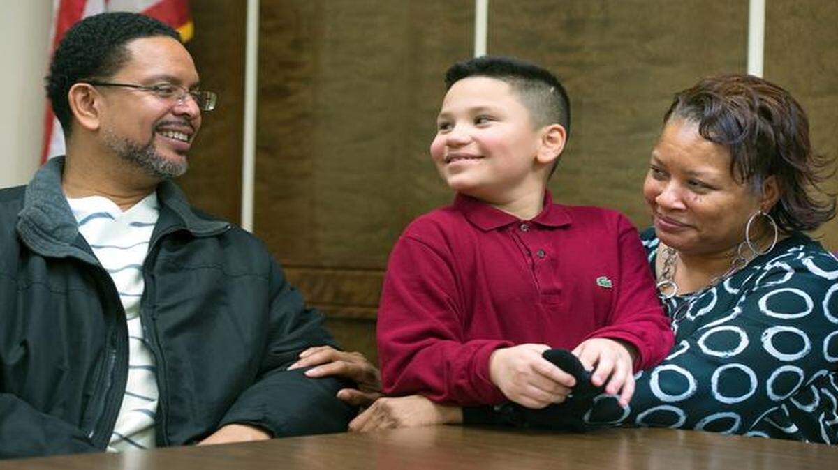 
After his adoption hearing, 8-year-old Adrian Davis (center) shared a smile with his new parents, Keith Davis and Loretta Davis. They adopted Adrian on Friday at the Jackson County Family Court in Kansas City. The couple also have adopted three older boys.
