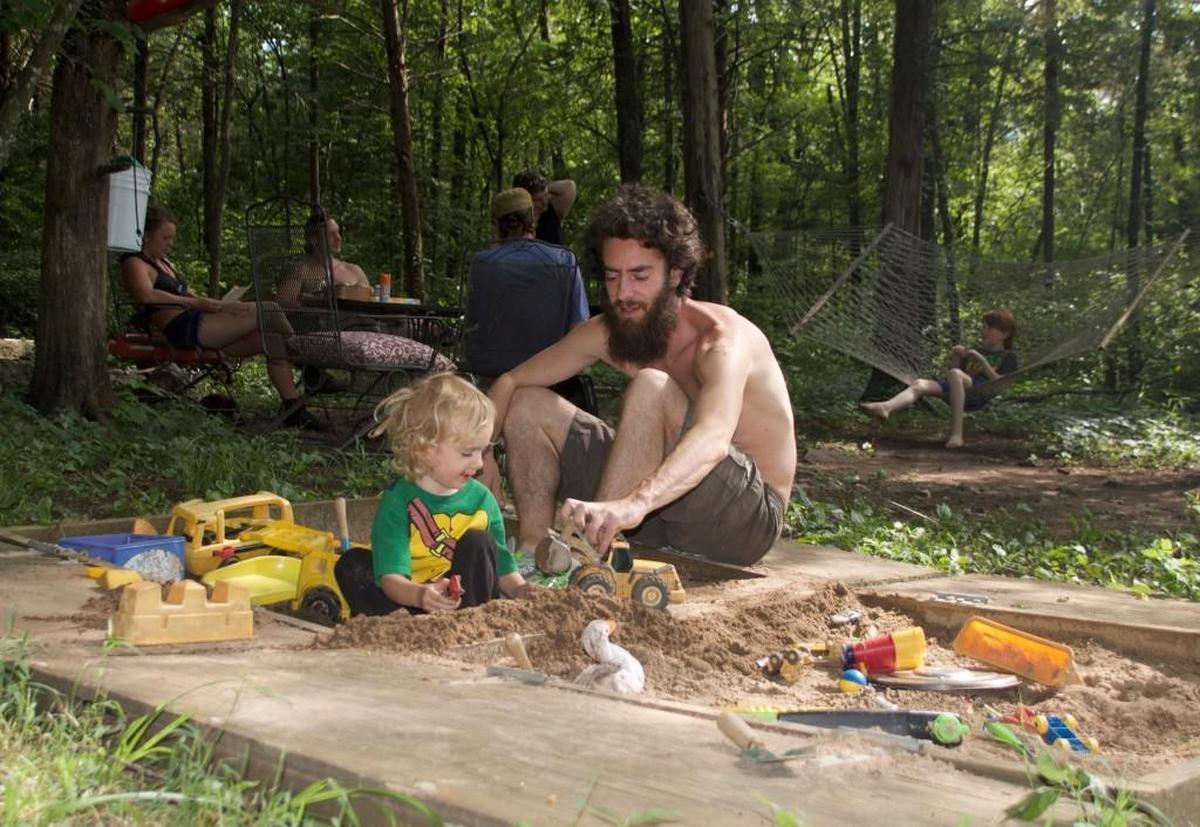 A man who gave his name as Loch Ness plays in a sandbox with his son, Taliesin, near the family residence at East Wind.