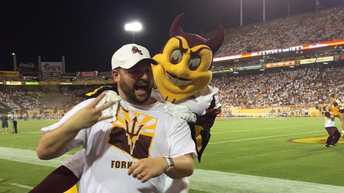 This photo courtesy of David Schapira shows ASU’s mascot Sparky jumping on Schapira at an Arizona State football game on Sept. 18, 2015 in Tempe, Ariz.
