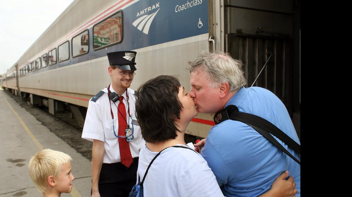 
Amtrak assistant conductor, Brandon Bostian stands by as Sandra Palmer, center, says goodbye to her boyfriend, Clyde Simpson, before he boards the train at the Amtrak station in St. Louis. Federal investigators have determined that an Amtrak train that crashed in Philadelphia on Tuesday, May 12, 2015, killing at least seven people, was careening through the city at 106 mph before it ran off the rails along a sharp curve. The attorney for Bostian, the engineer at the controls of the train, said Thursday, his client has no recollection of the accident. 
