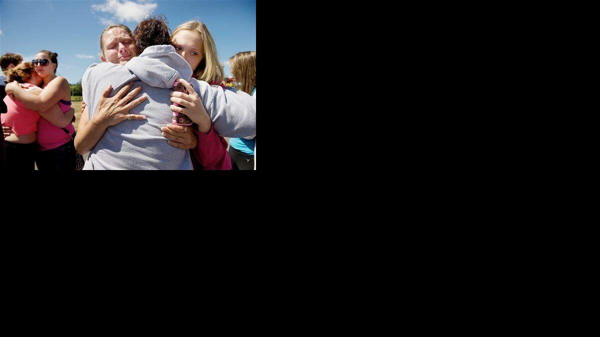 
Brandi Wilson, left, and her daughter, Trisha Wilson, 15, right, embrace Trish Hall, a mother waiting for her student, as students arrived at the Fred Meyer grocery store parking lot in Wood Village, Ore., after a shooting at Reynolds High School Tuesday, June 10, 2014, in nearby Troutdale. A gunman killed a student at the high school east of Portland Tuesday and the shooter is also dead, police said.
