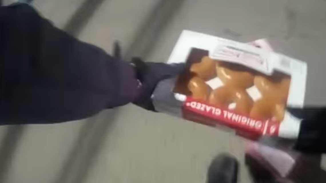 An officer is shown picking up a box of doughnuts that flew out of a Krispy Kreme truck that was stolen in Indianapolis.