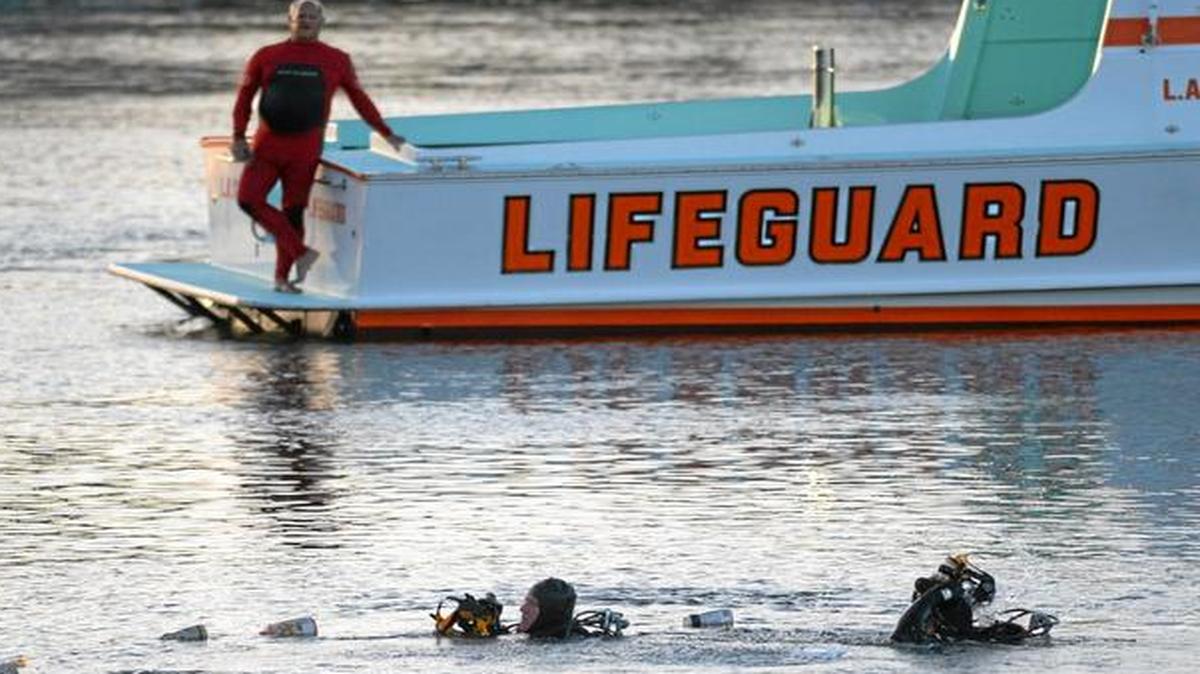 
Divers emerge from the water as debris believed to be from a car floats to the surface at the San Pedro Slip, in San Pedro, Calif.
