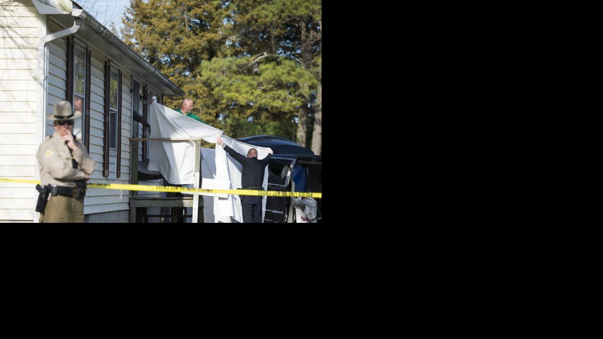 
Sheets are held as a body is removed from a residence where police say seven children and one adult have been found dead Monday in Princess Anne, Md. 
