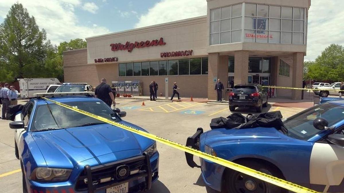 Police cordon off a scene where a woman was shot and a man was killed trying to stop a suspect from fleeing from the parking lot of a Walgreens in Arlington, Texas