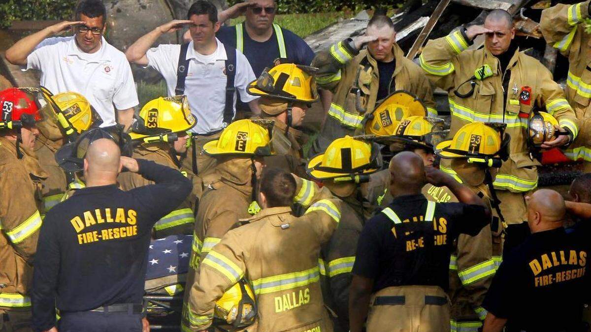 Dallas firefighters salute as the body of Stan Wilson is carried from the scene of a six-alarm fire on May 20, 2013. Authorities later determined that a commander’s decision to send Wilson and his crew into a building in danger of collapse was a contributing cause of his death.