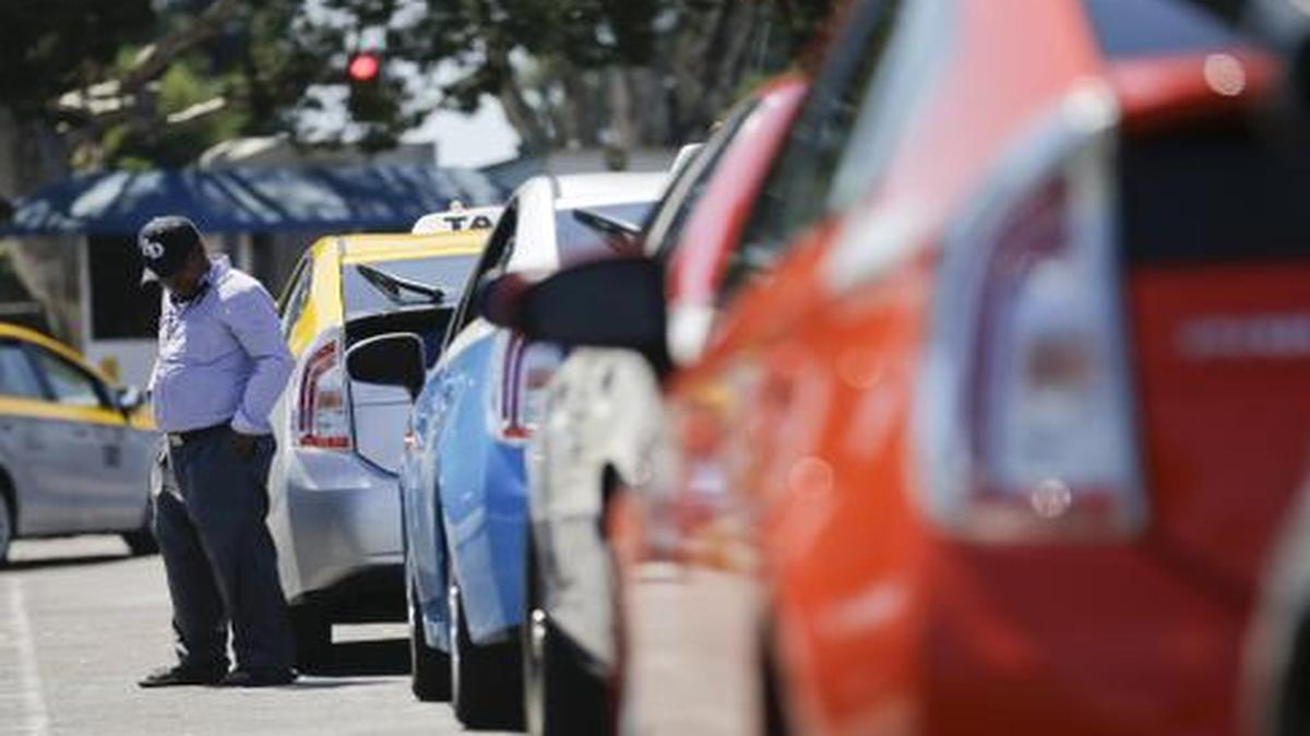 
A cab driver waits near his car in line at a depot near the airport Wednesday, Sept. 10, 2014, in San Diego.
